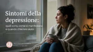 Persona adulta seduta accanto a una finestra in luce tenue, con espressione stanca e assorta — immagine dedicata ai sintomi della depressione
